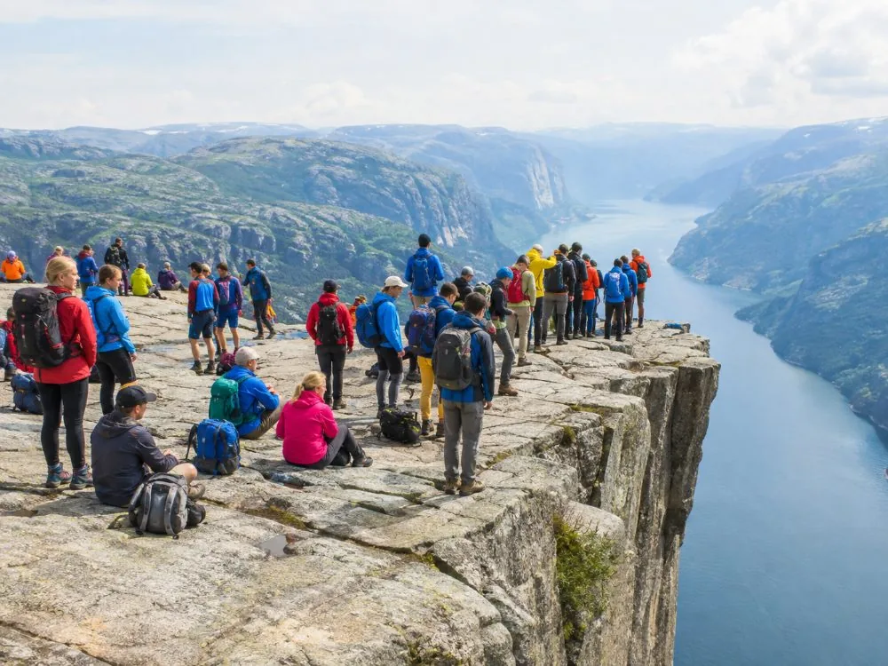 Walkers sitting and standing on the unfenced edge of the Preikestolen plateau